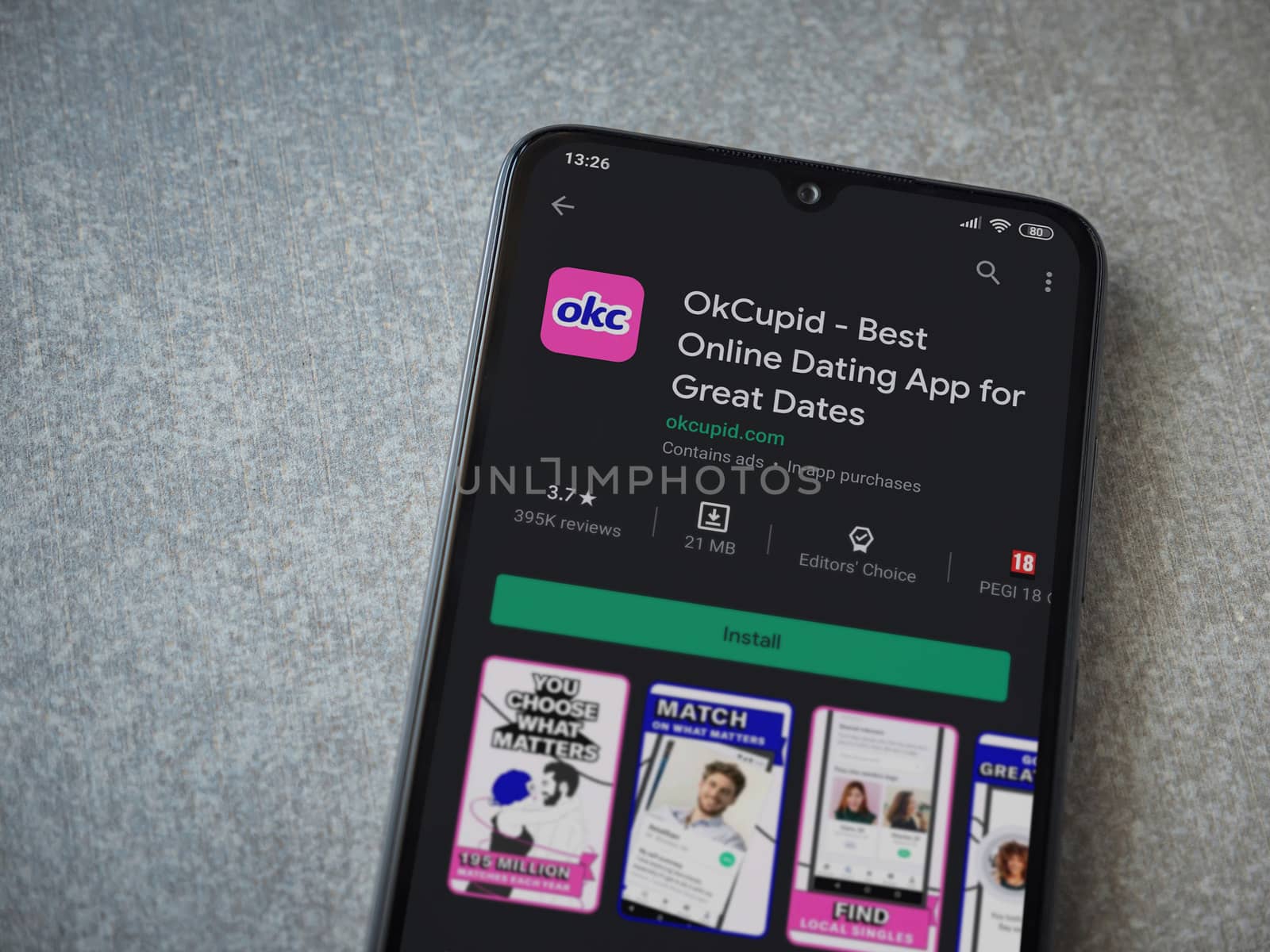 Lod, Israel - July 8, 2020: OkCupid app play store page on the display of a black mobile smartphone on ceramic stone background. Top view flat lay with copy space.