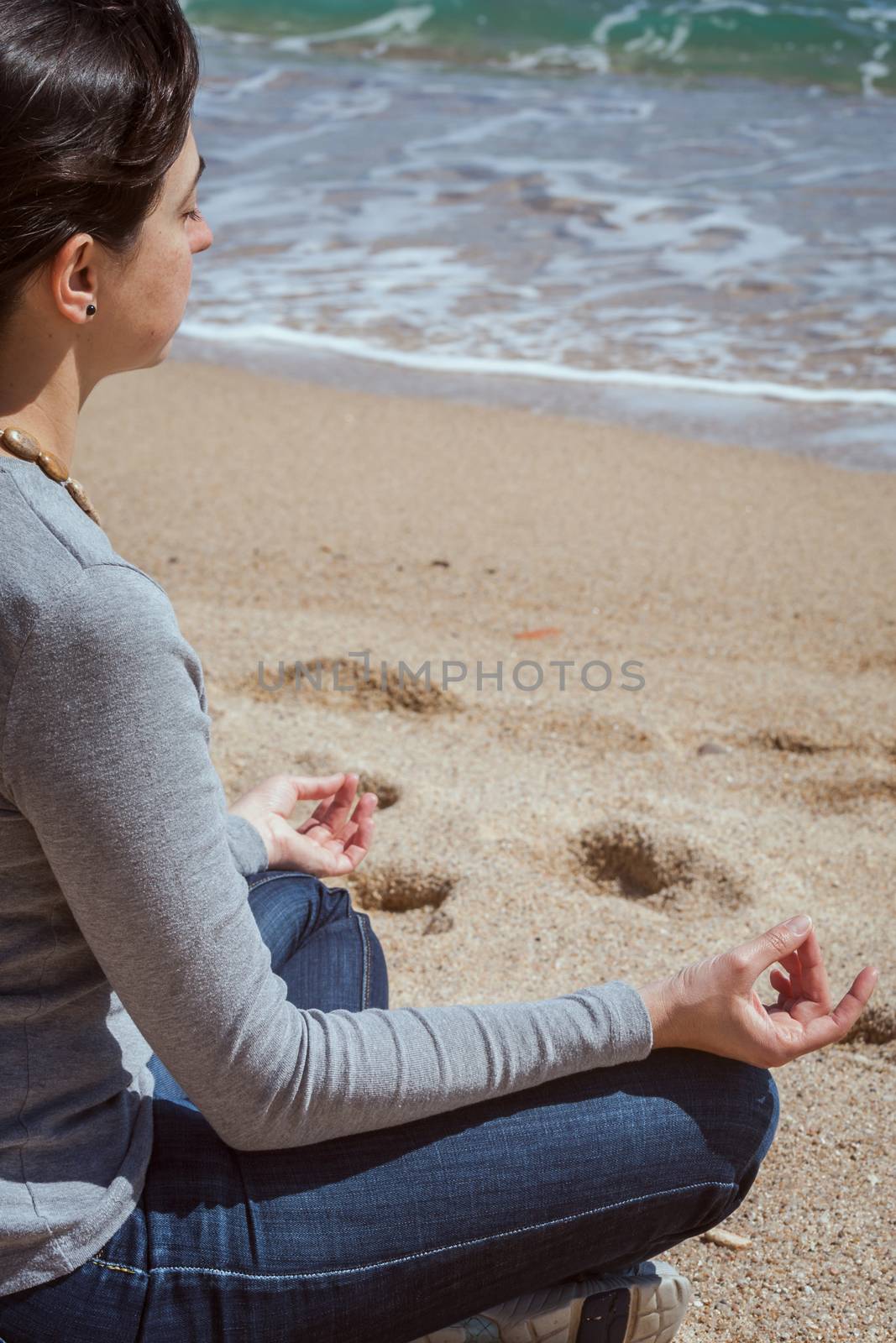 Body detail of a beautiful girl in a meditation on the beach