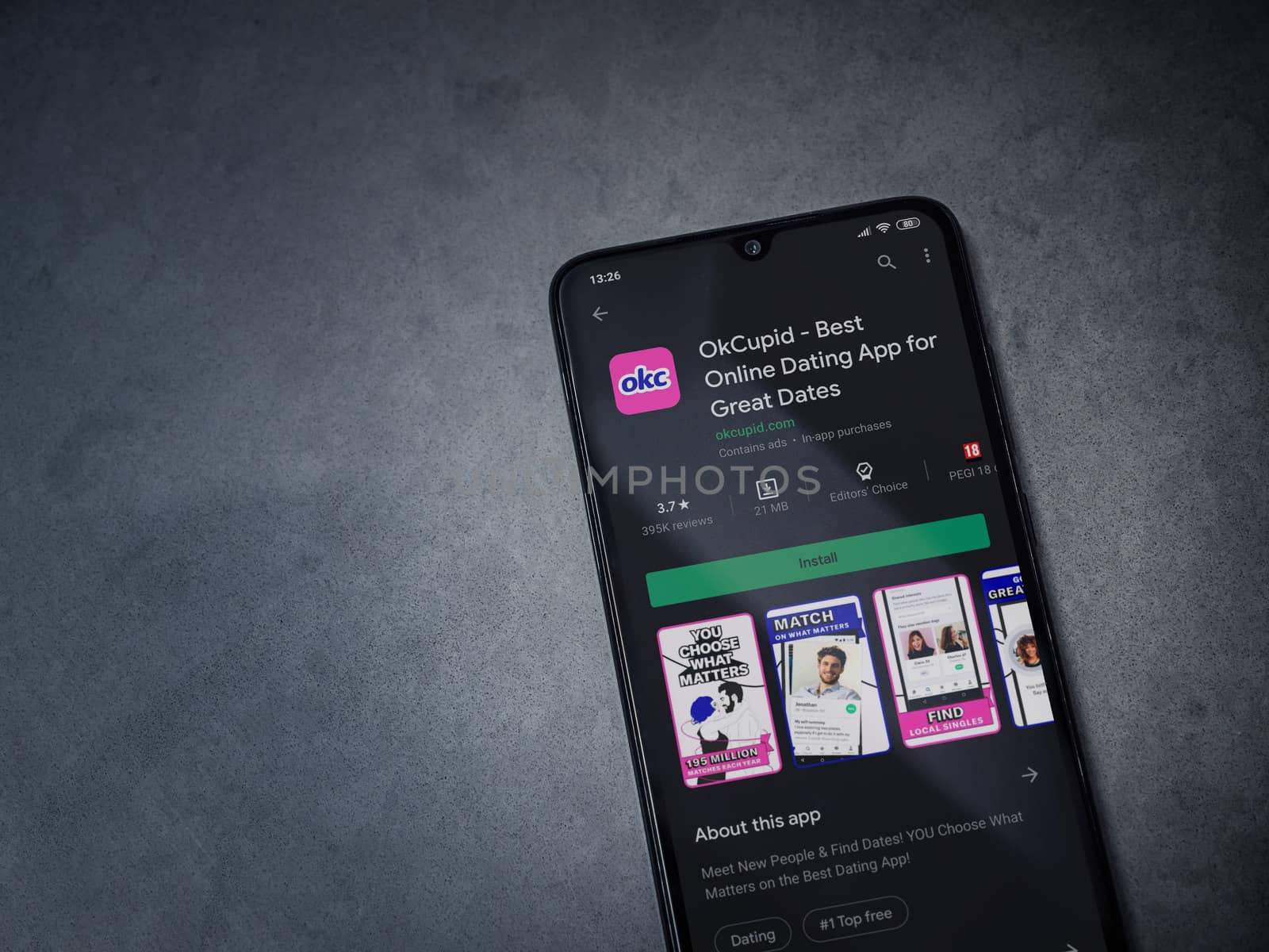 Lod, Israel - July 8, 2020: OkCupid app play store page on the display of a black mobile smartphone on dark marble stone background. Top view flat lay with copy space.