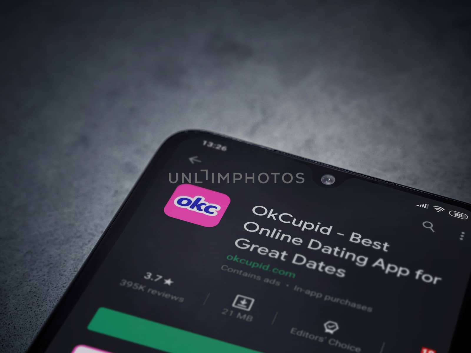 Lod, Israel - July 8, 2020: OkCupid app play store page on the display of a black mobile smartphone on dark marble stone background. Top view flat lay with copy space.