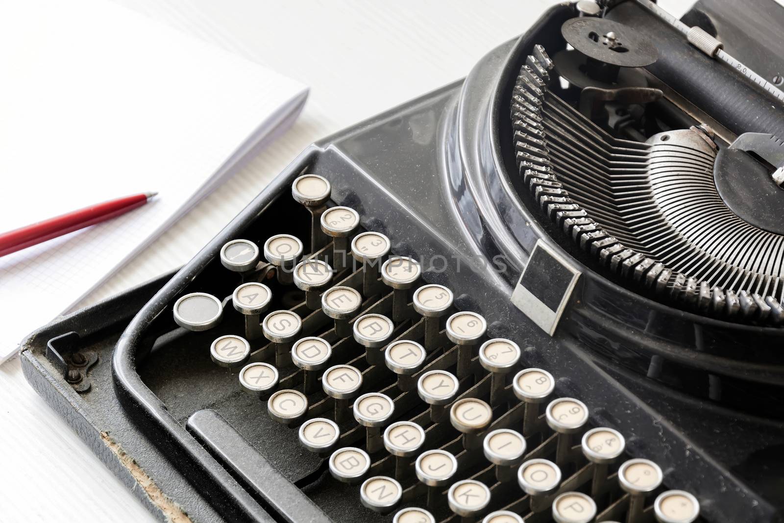 an old black typewriter next to a white sheet of paper with a red pen. Journalism and writing tools. Storytelling and creative activity