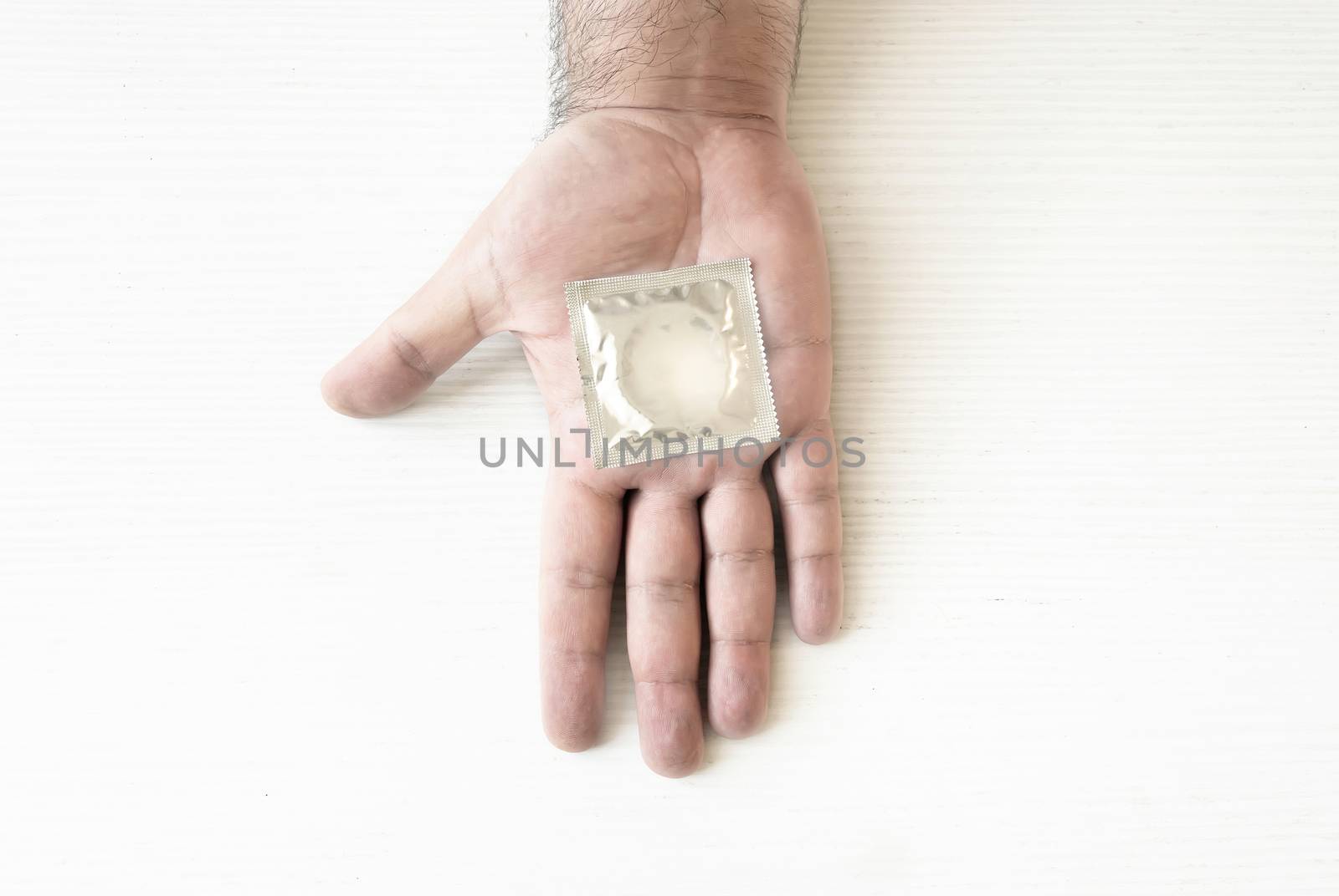 a condom packed on the palm of a male hand. Health and contraception. Prevention of sexually transmitted diseases. Safe sex
