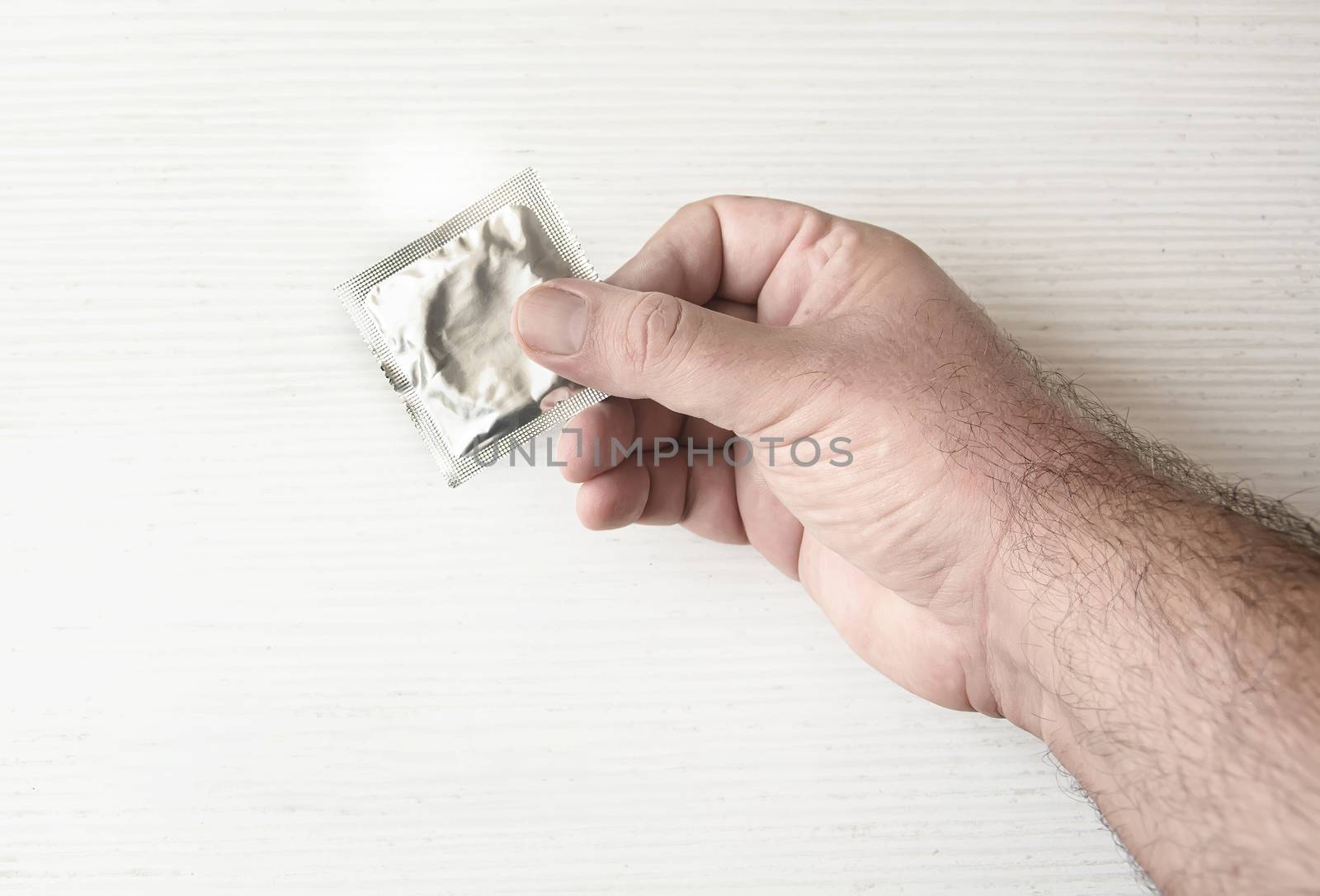 A male hand holding a condom packed. Health and contraception. Prevention of sexually transmitted diseases. Safe sex