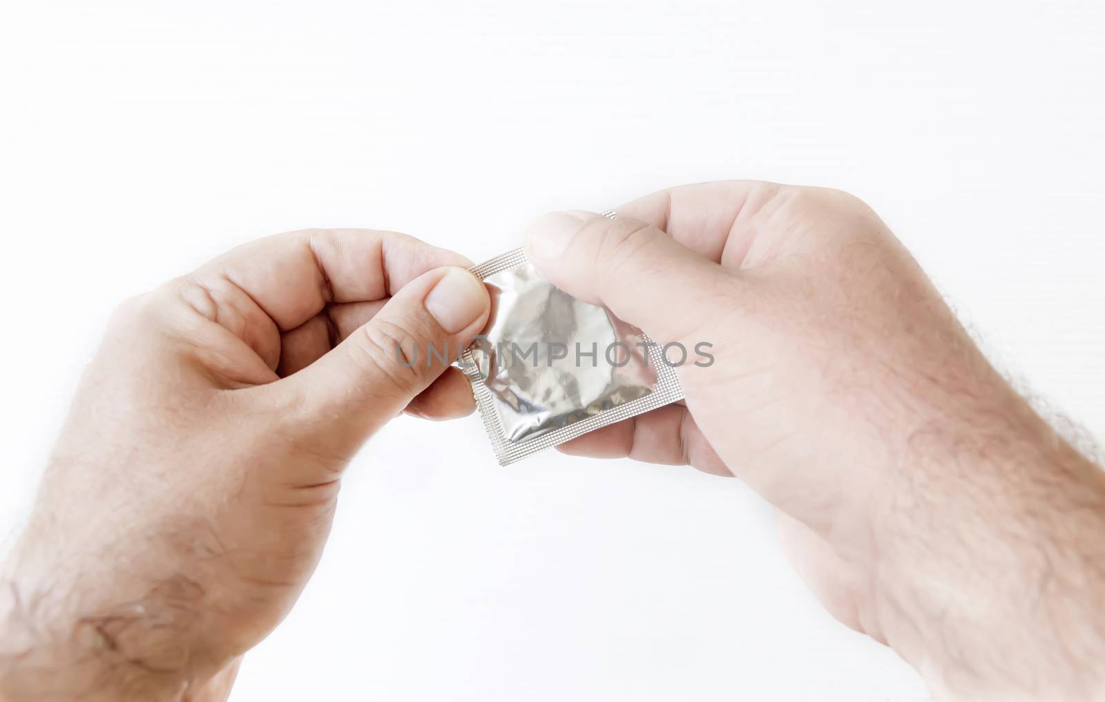 male hands while opening the package of a condom by rarrarorro