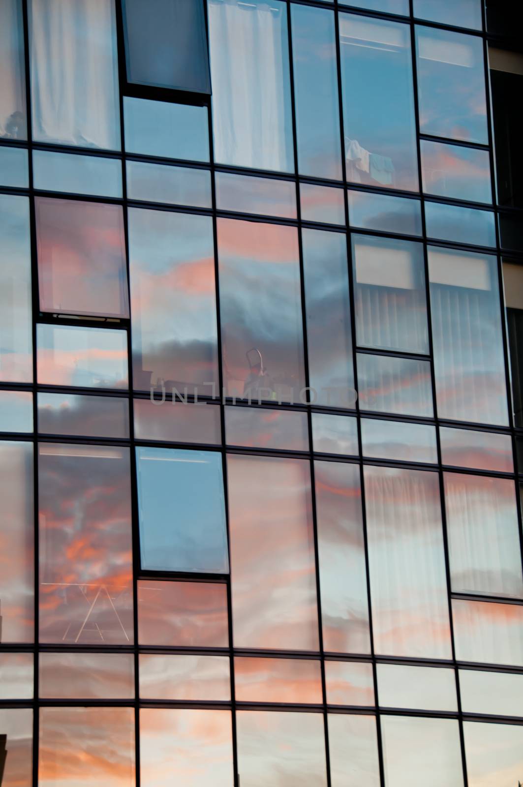 Reflection of pastel Sun set on window glass of modern corporate by eyeofpaul
