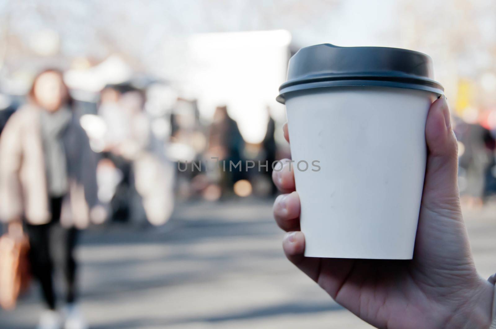Take away white paper hot coffee cup with right hand holding in Sunday flea market