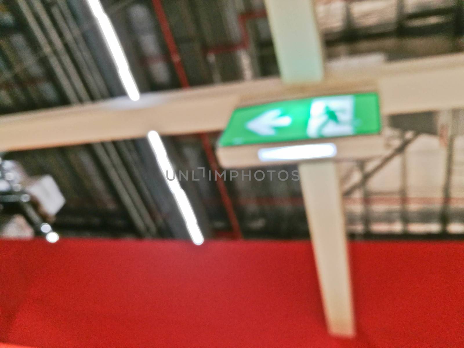 Defocused blurry scene of Emergency exit route sign on top of factory warehouse