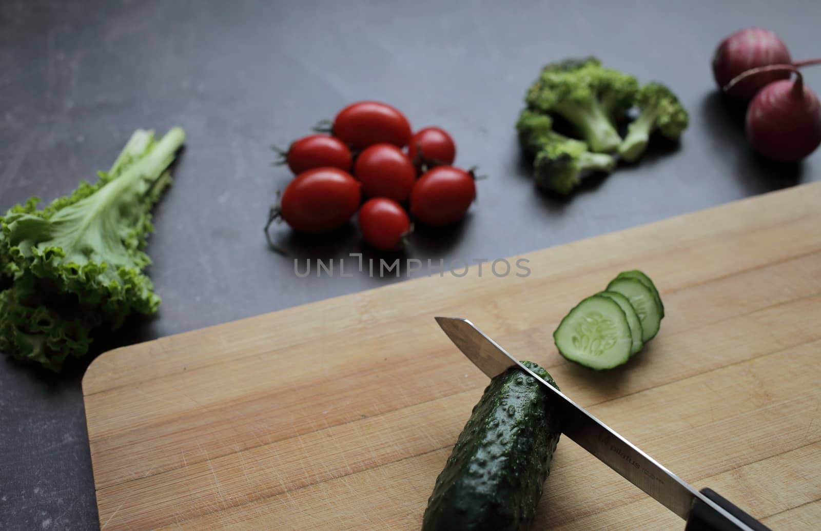 Fresh vegetables on a cutting board on a gray table Tomatoes, lettuce, broccoli, radish