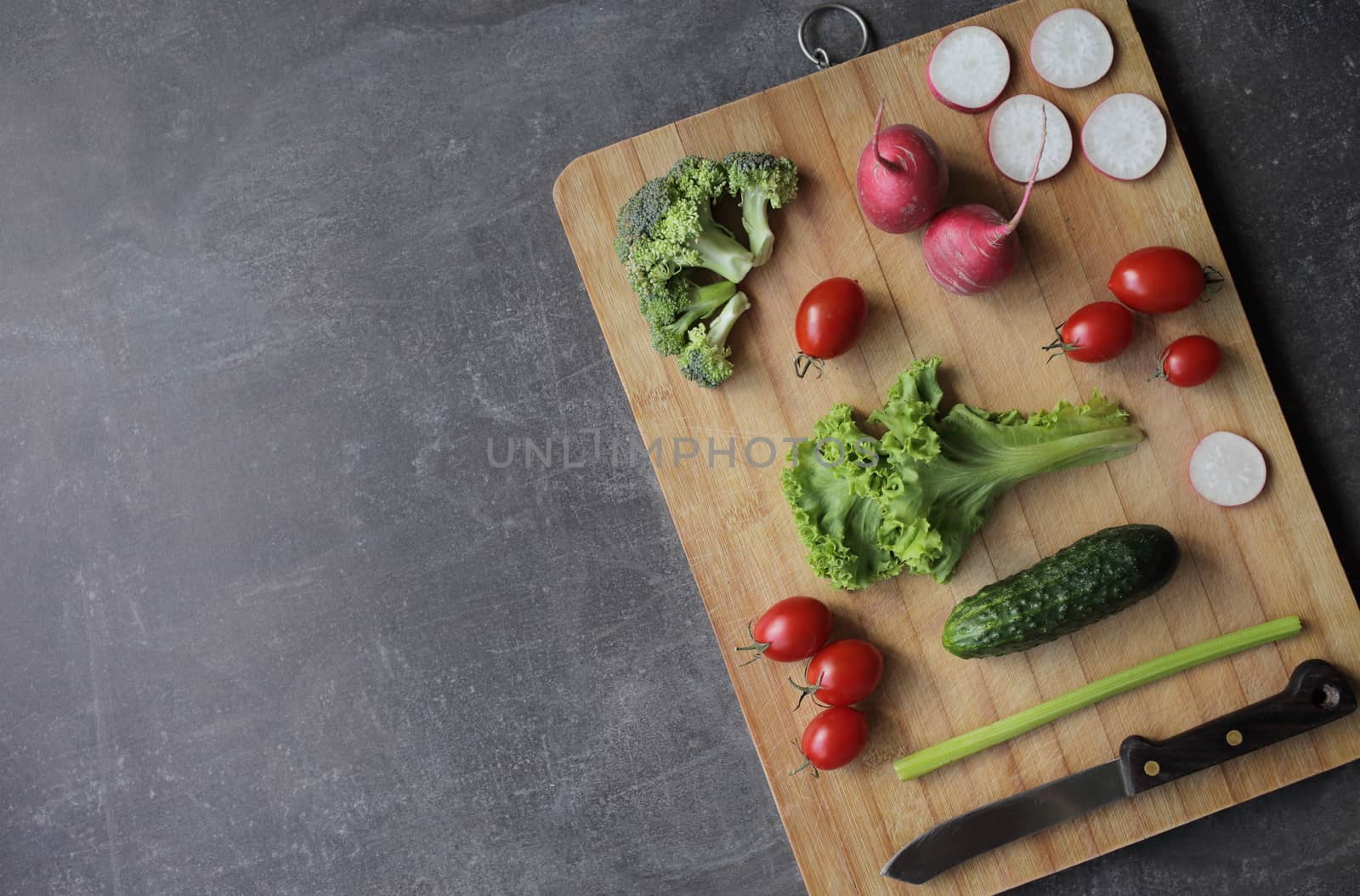 Fresh vegetables on a cutting board on a gray table by selinsmo