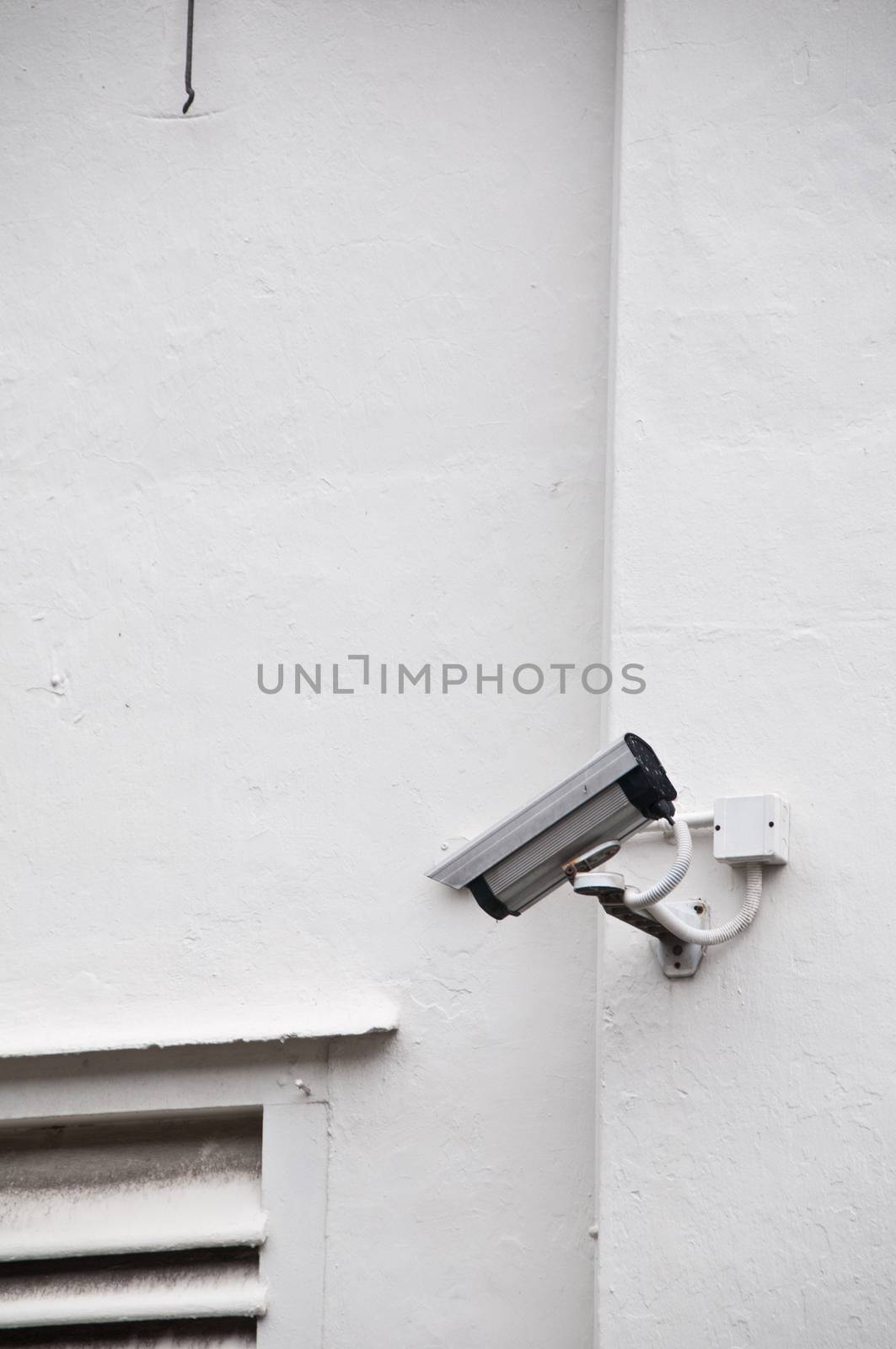 Surveillance camera on white wall by eyeofpaul