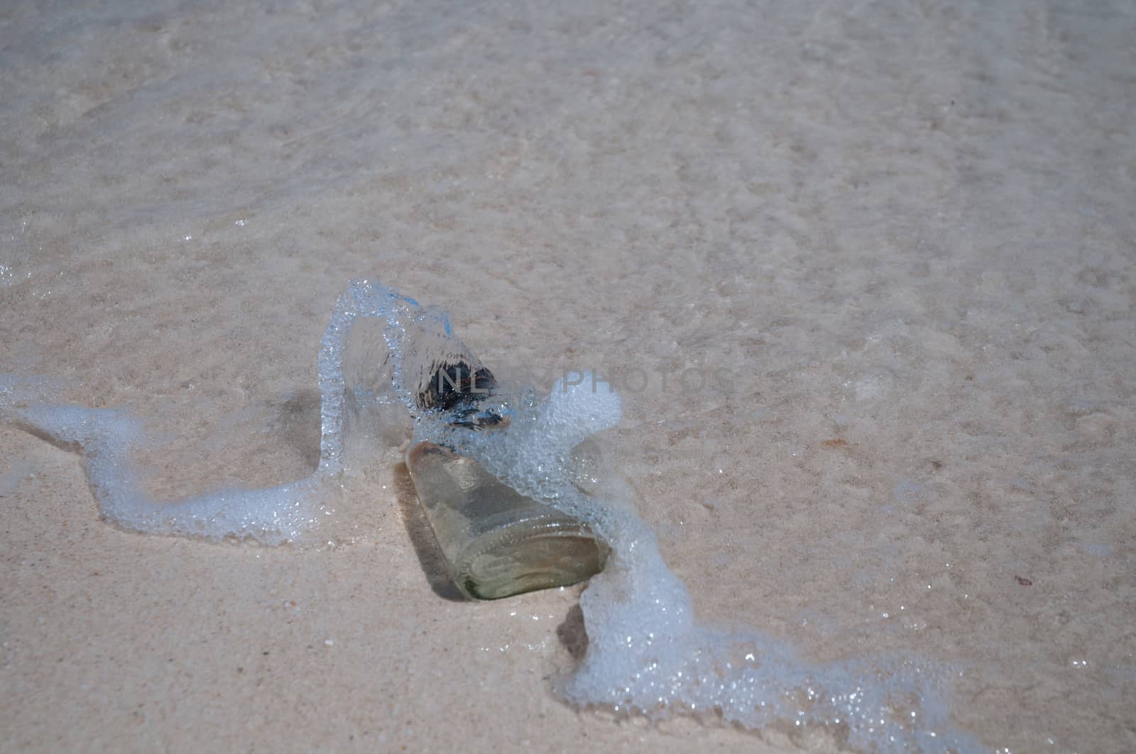 Empty bottle on a beach and wave by eyeofpaul