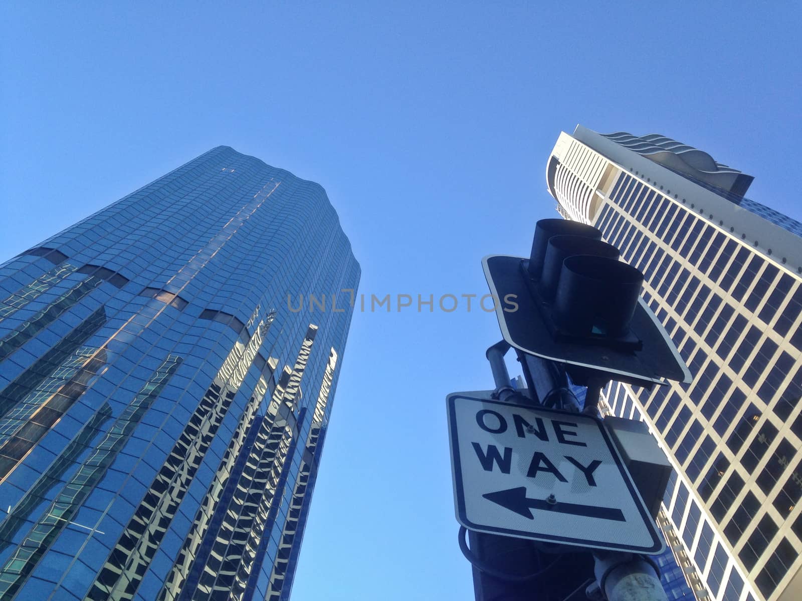 One way traffic sign under corporate buildings blue sky by eyeofpaul