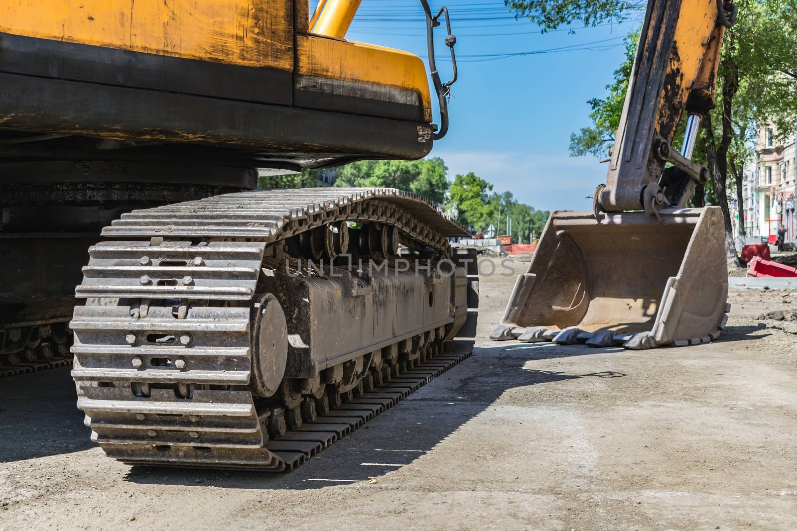 Crawler tracks and excavator bucket at construction site close up