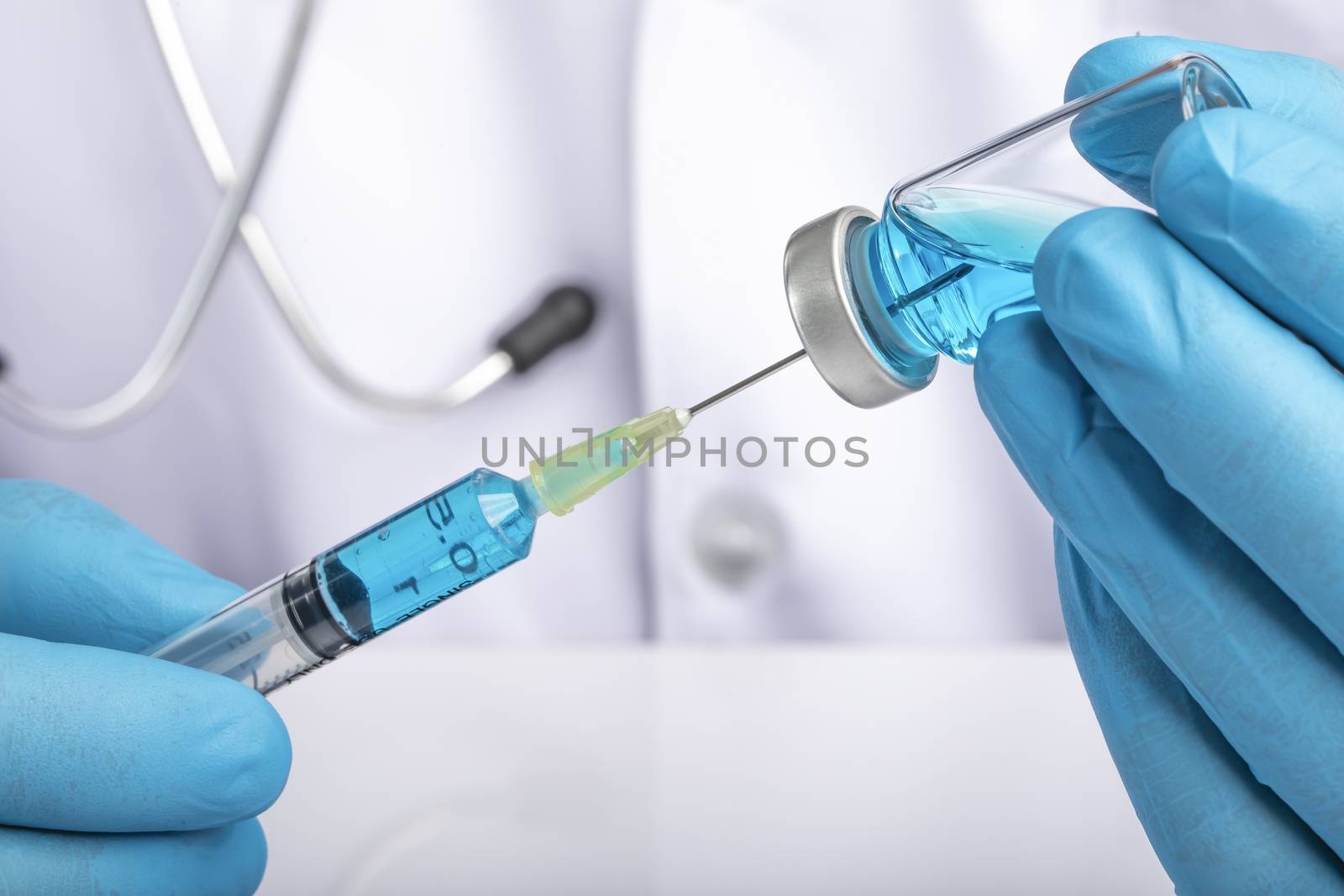 A doctor in white coat drawing clear light blue liquid from a vial into a syringe. Medication or vaccine adminstration, covid-19 prevention concept.
