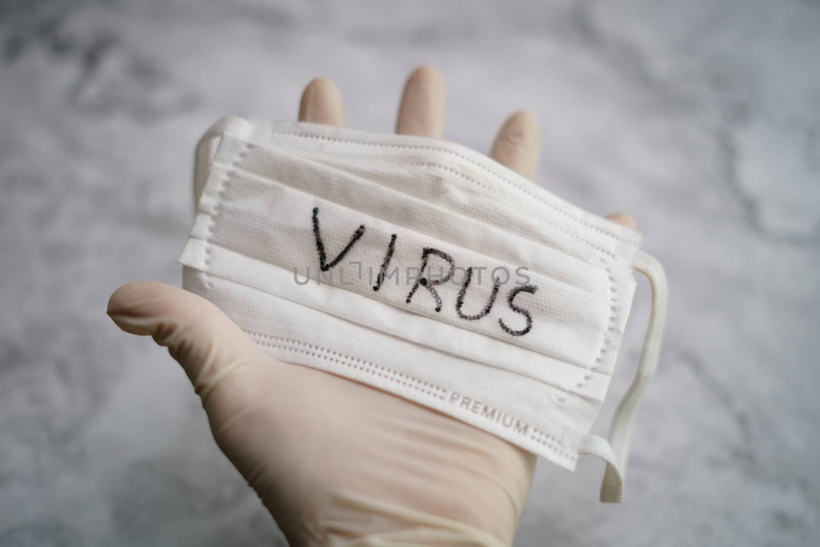 Hand holding medical protective mask with virus text.