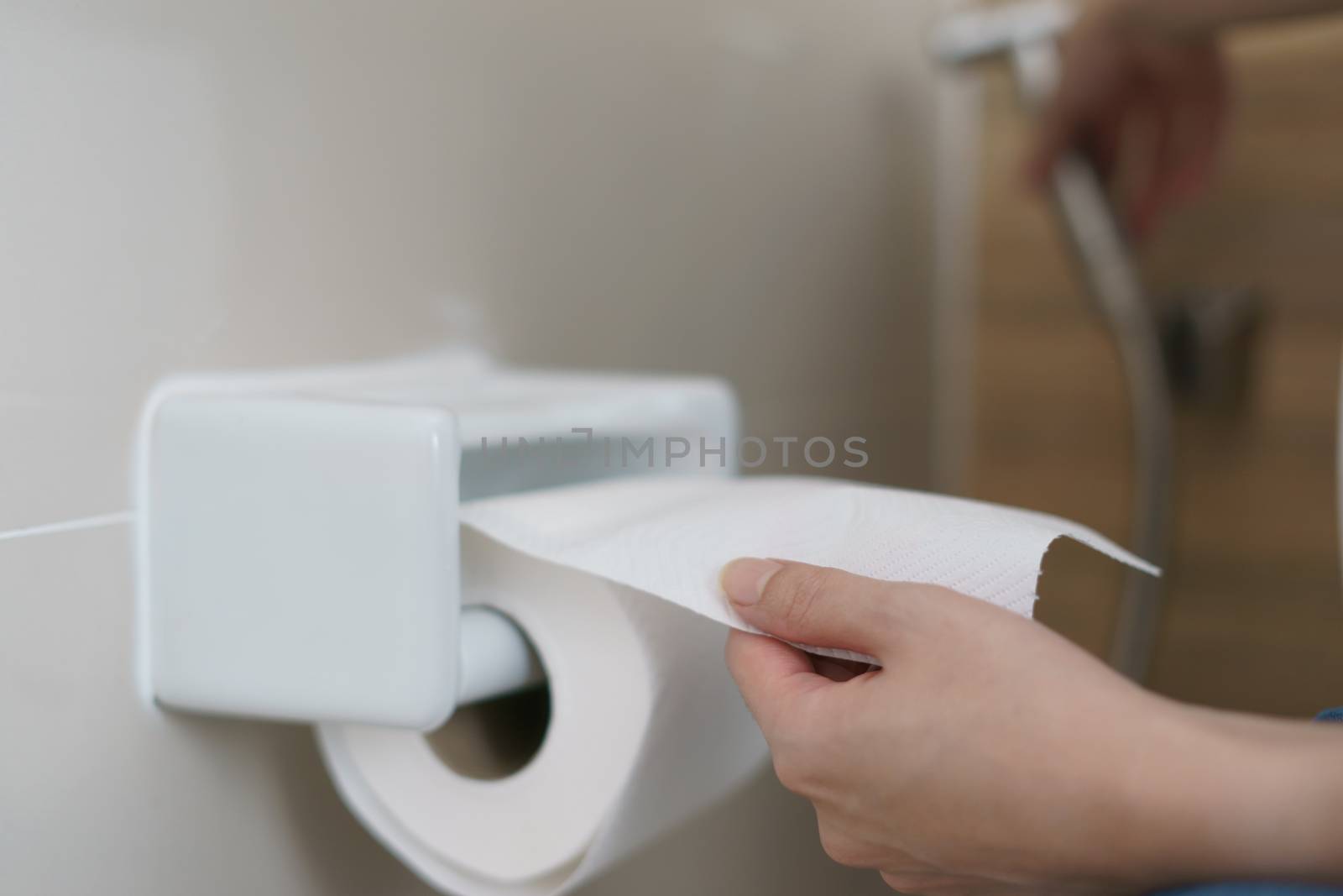 Hand pulling a roll of toilet paper tissue.