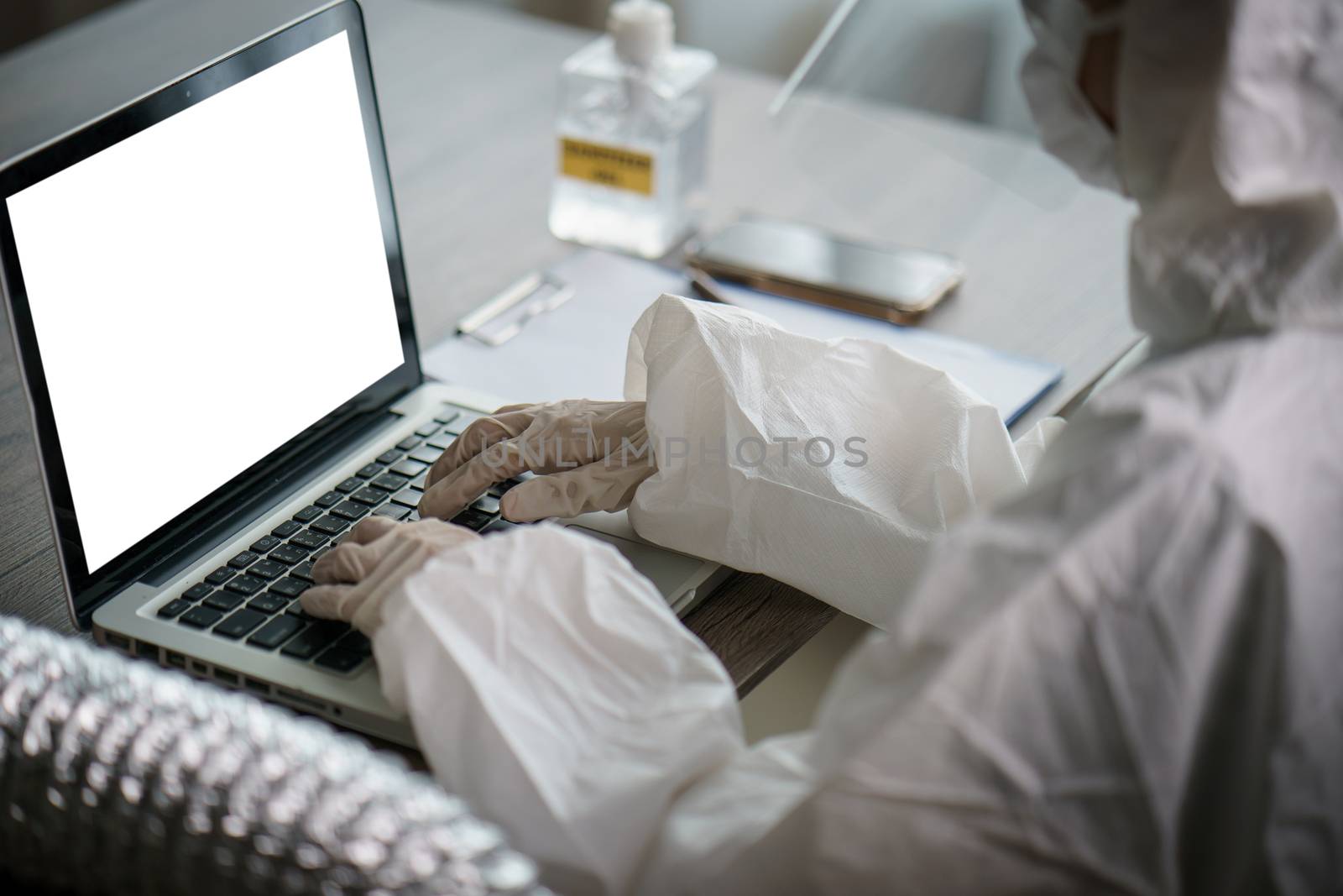 Woman in protective hazmat suit worker in laboratory computer analyzing in laboratory. to stop spreading coronavirus or COVID-19.