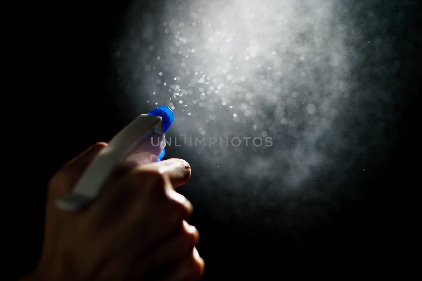 Woman's hands with blue foggy spraying disinfectant to stop spreading coronavirus or COVID-19.