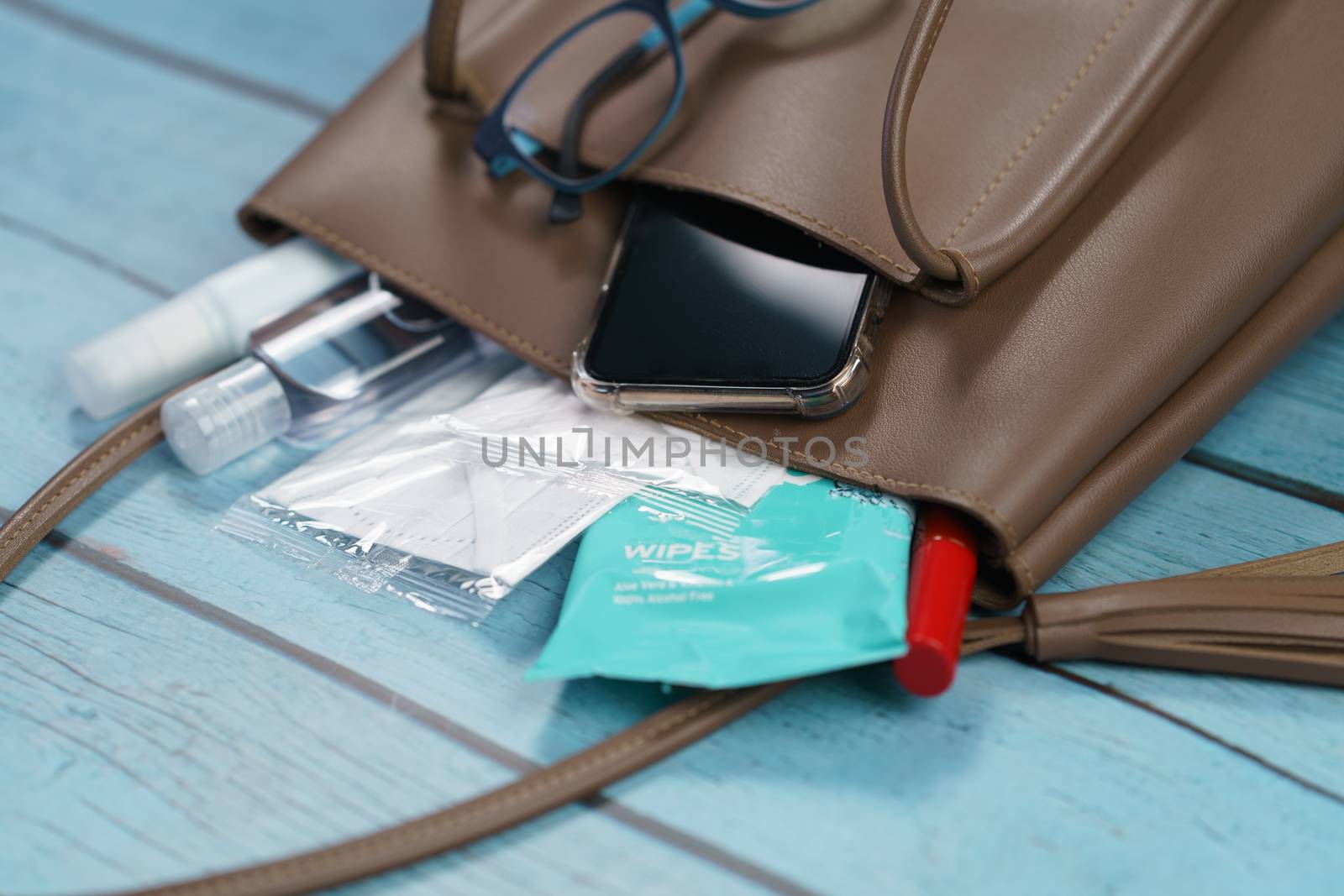 Hand bag with 2020 must have items smart phone, protective face mask, glasses and sanitizer gel corona virus or Covid-19 protection.
