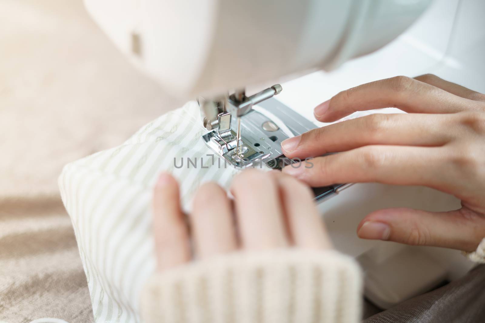 Closeup of woman hand using the sewing machine to sew the face mask during the coronavirus pandemia.