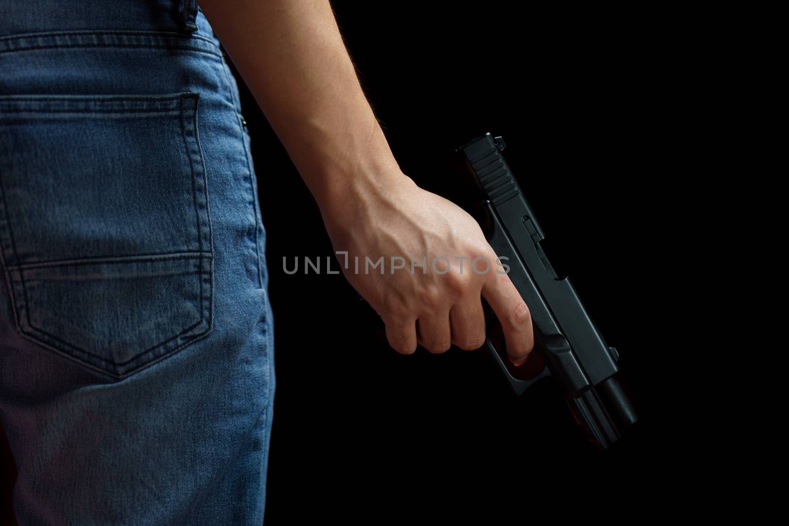 Man holding a gun side him on black background. by sirawit99