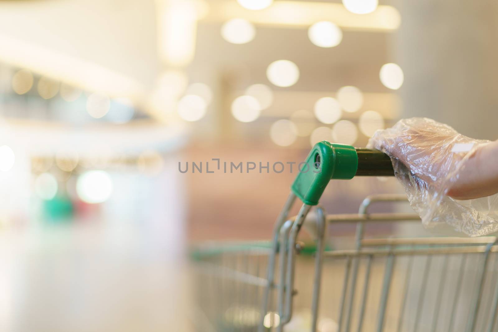 Blurred of supermarket with hand hold empty shopping cart. by sirawit99