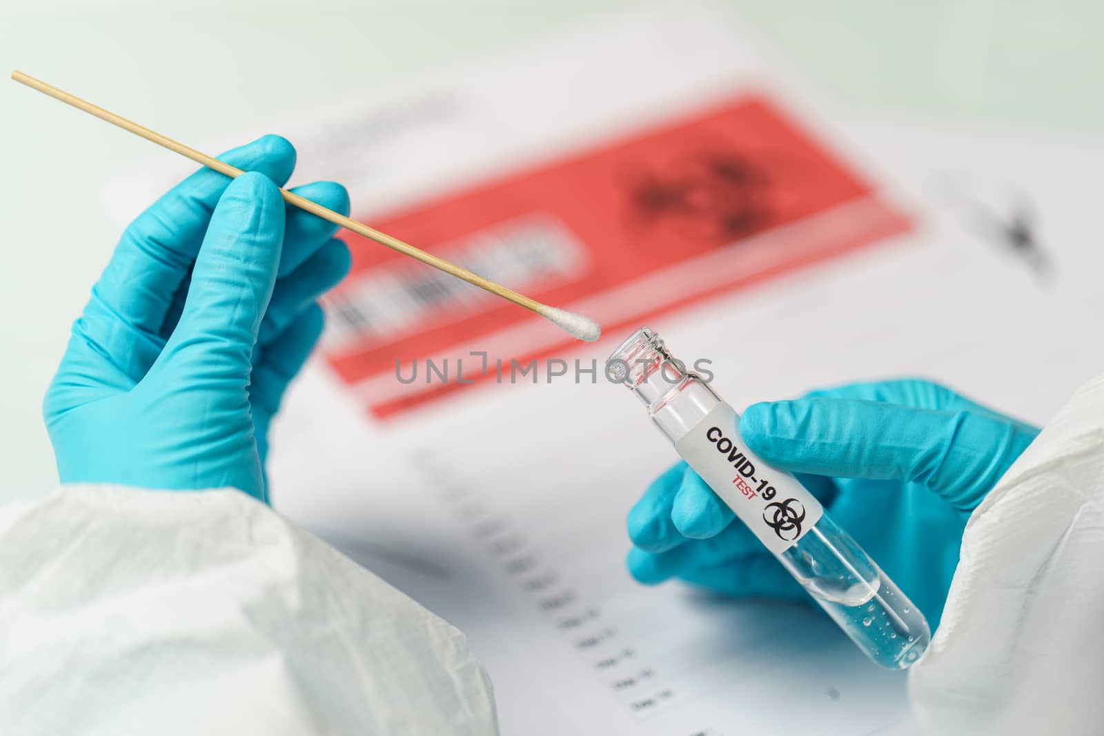 Hand holding COVID-19 swab collection kit, specimen sample testing process.