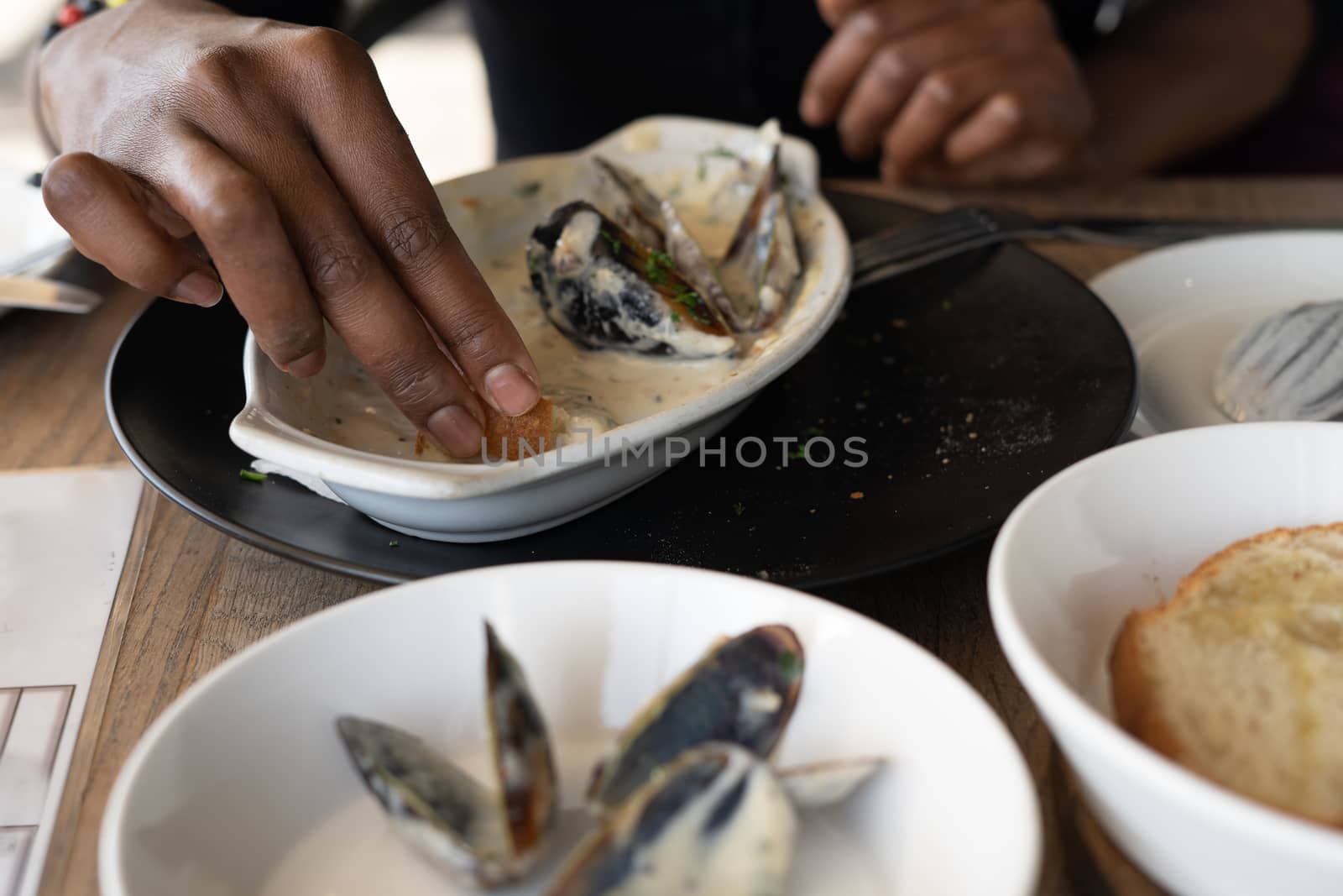 Woman eating mussels out of plate at restaurant by rushay