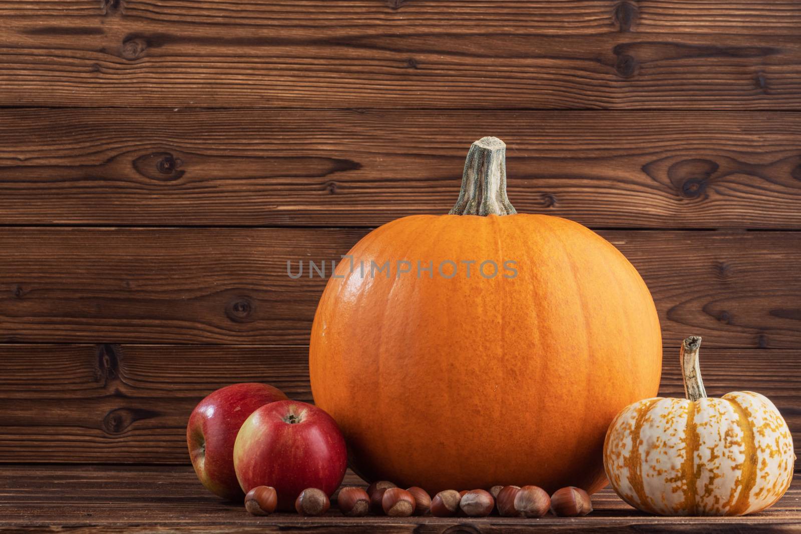 Autumn harvest still life with pumpkins , apples , hazelnuts on wooden background