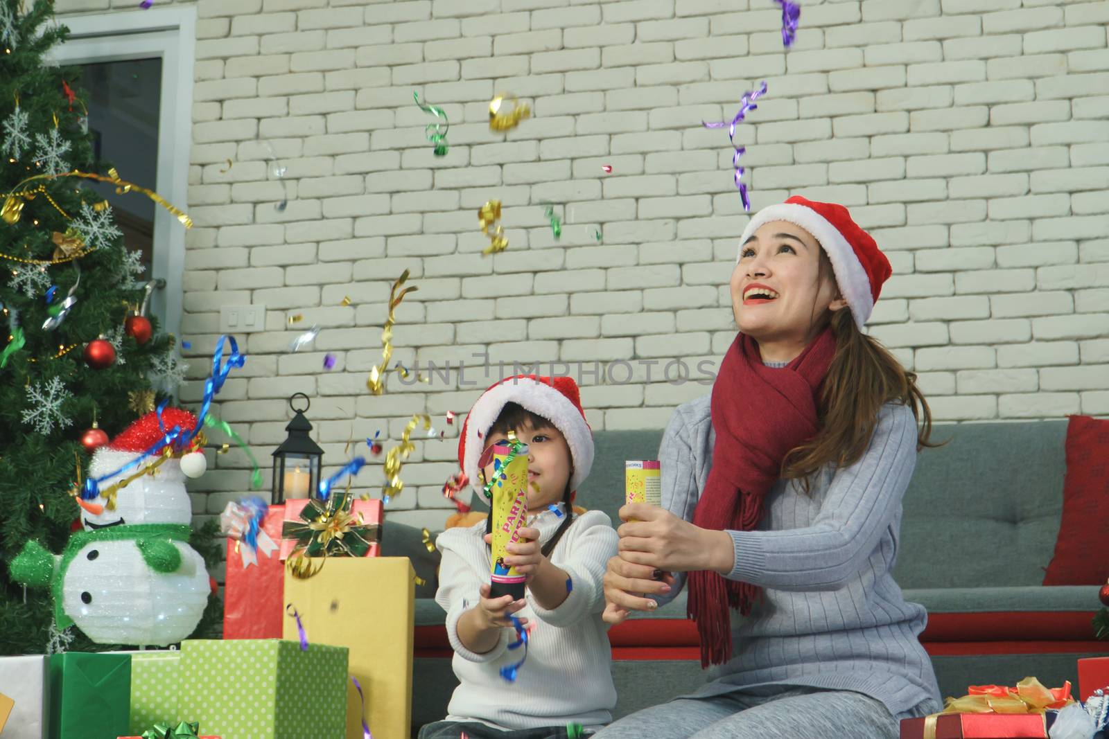 Asian family Happy Christmas and New Year holidays. The mother and daughter prepare to wrap the gift box. And decorate the Christmas tree. The festive season is beginning.