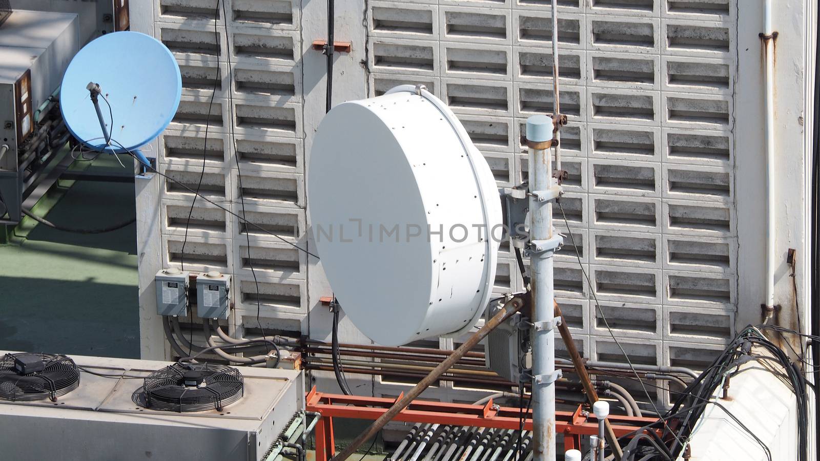 Old big telecommunication satellite dish on roof top of building.