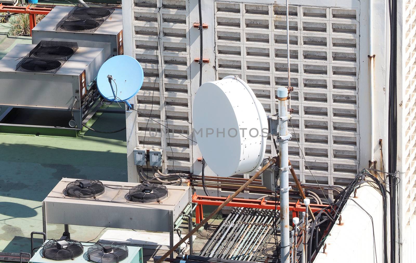 Old big telecommunication satellite dish on roof top of building.