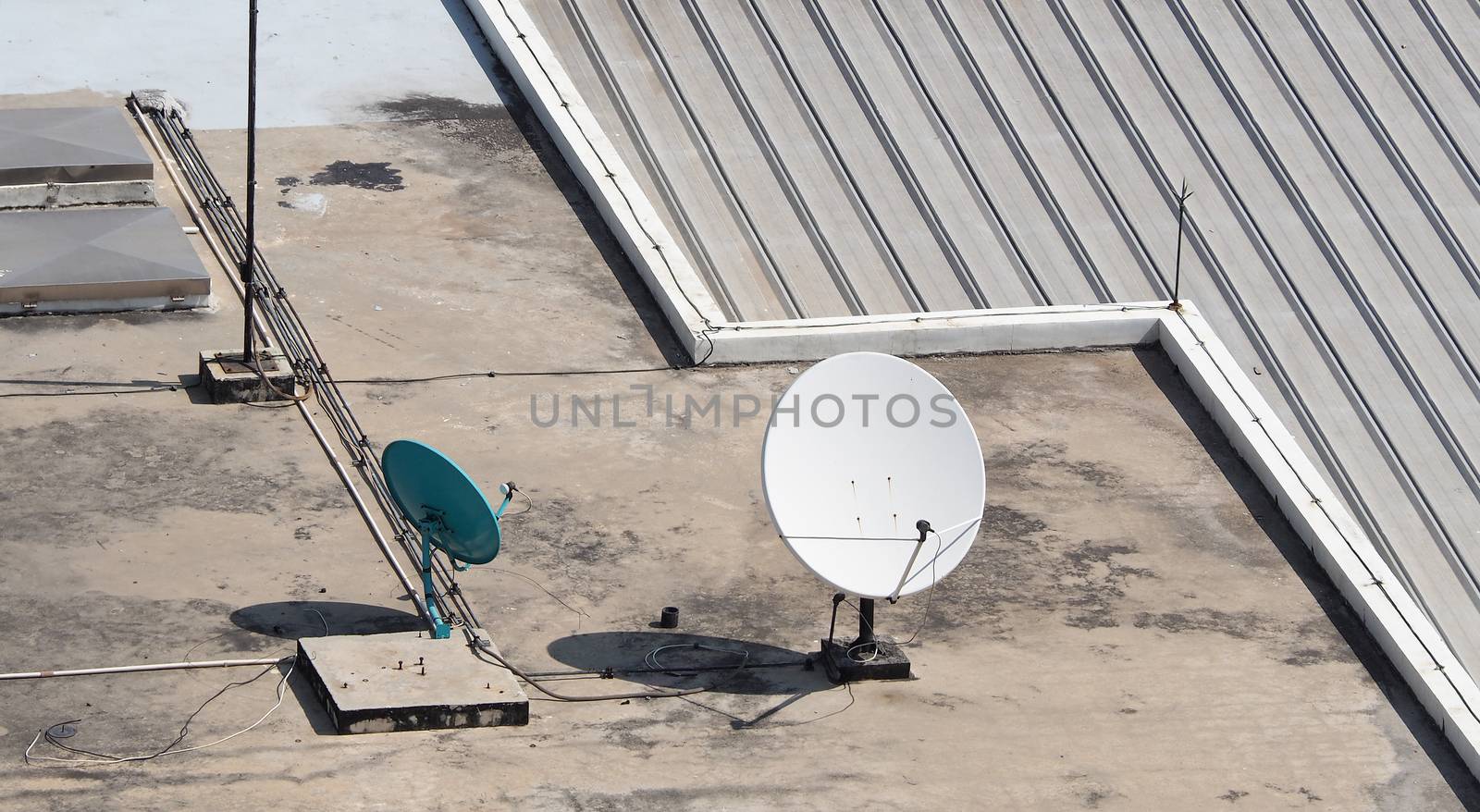 Old big telecommunication satellite dish on roof top of building.