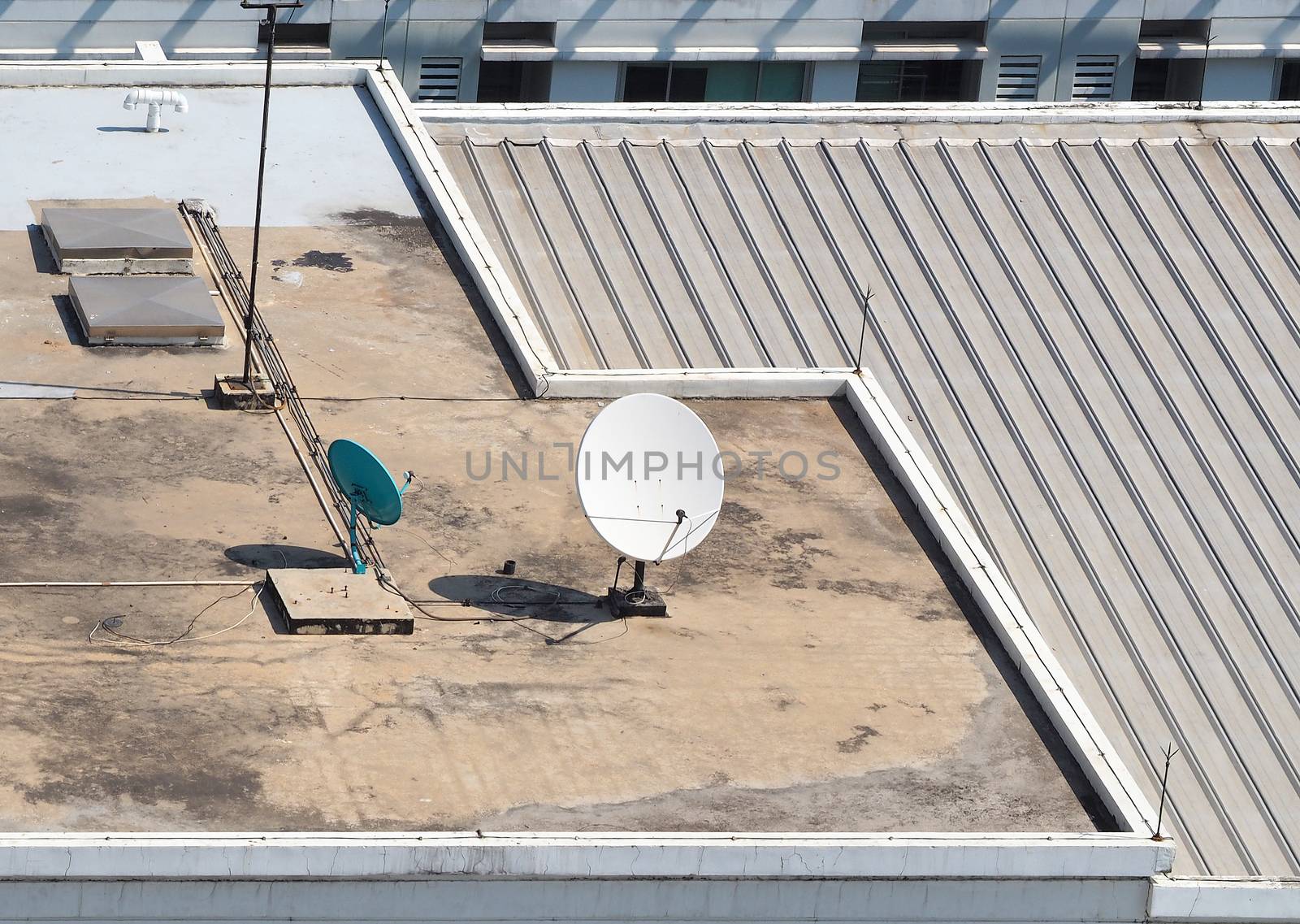 Old big telecommunication satellite dish on roof top of building.