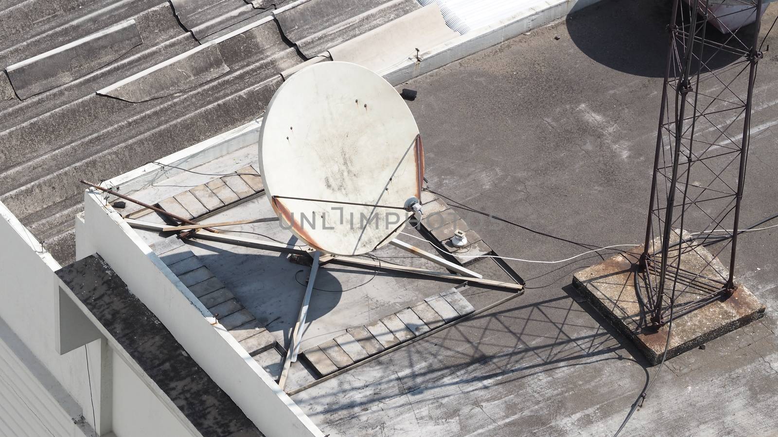 Old big telecommunication satellite dish on roof top of building.