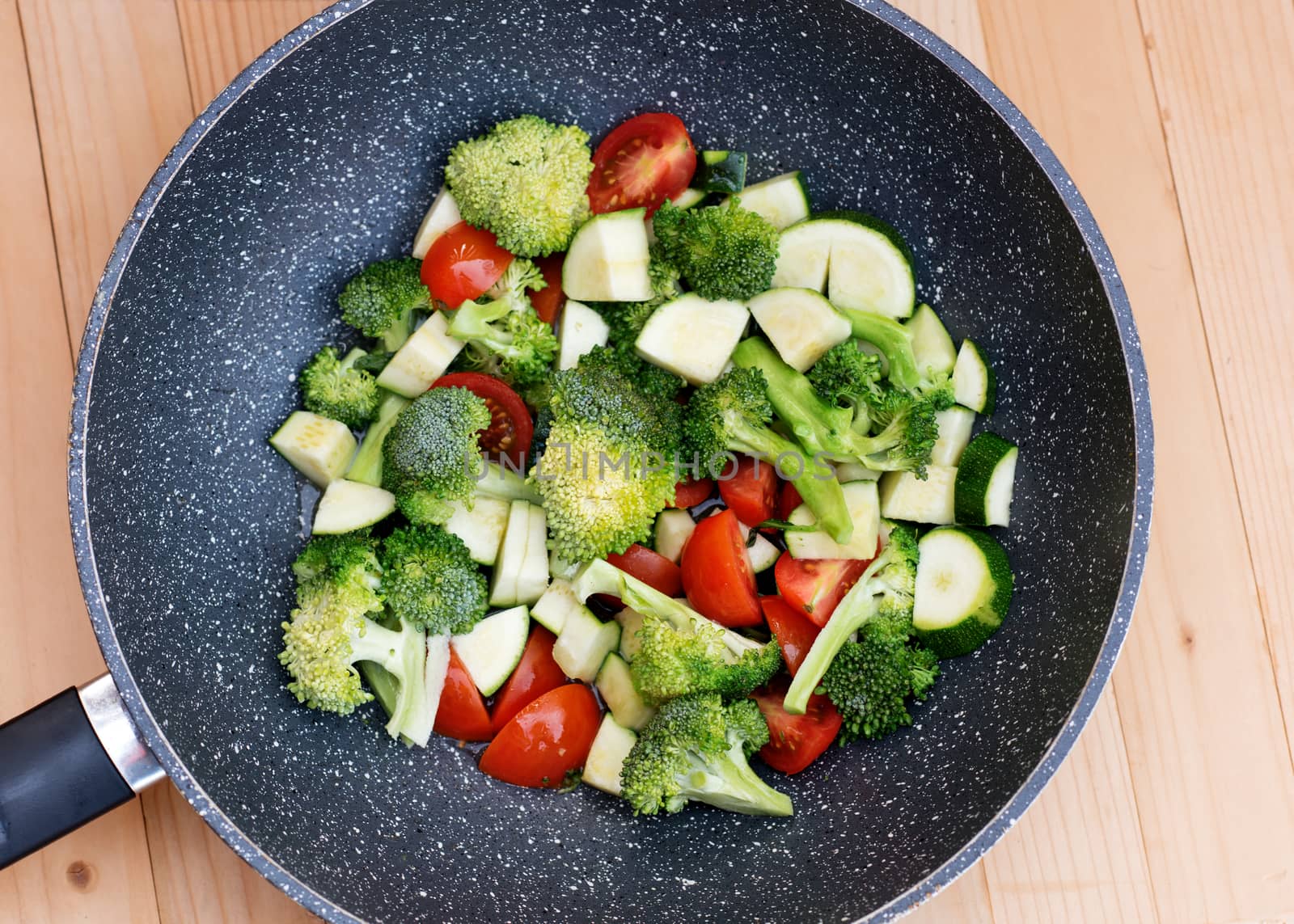 Green vegetables, broccoli, zucchini, tomatoes in a VOC pan