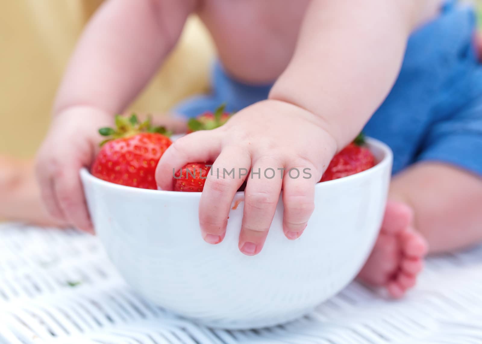 a child grabbing strawberries from a bowl