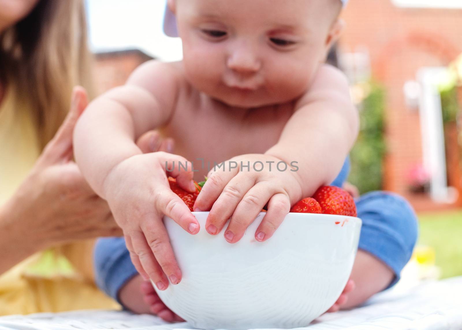 a child grabbing strawberries from a bowl