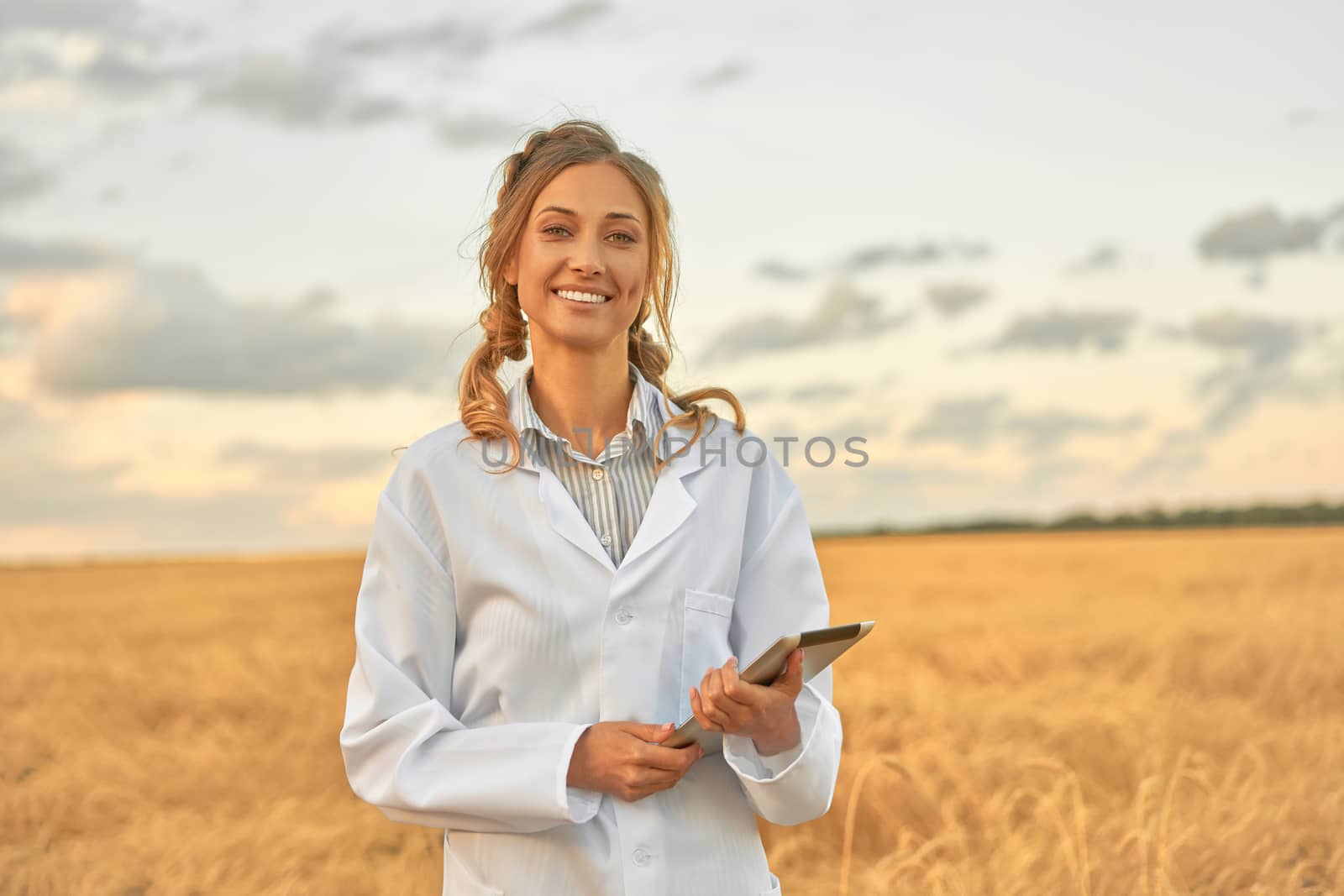 Woman farmer white coat smart farming standing farmland smiling using digital tablet Female agronomist specialist research monitoring analysis data agribusiness Caucasian worker agricultural field
