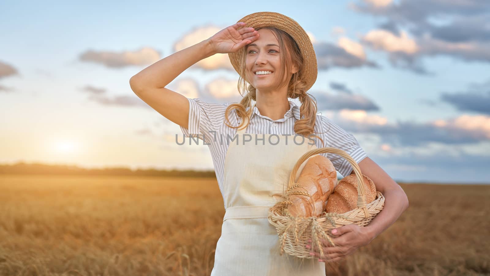 Woman baker holding wicker basket bread eco product Female farmer standing wheat agricultural field Baking small business Caucasian person dressed straw hat apron organic healthy food concept Banner