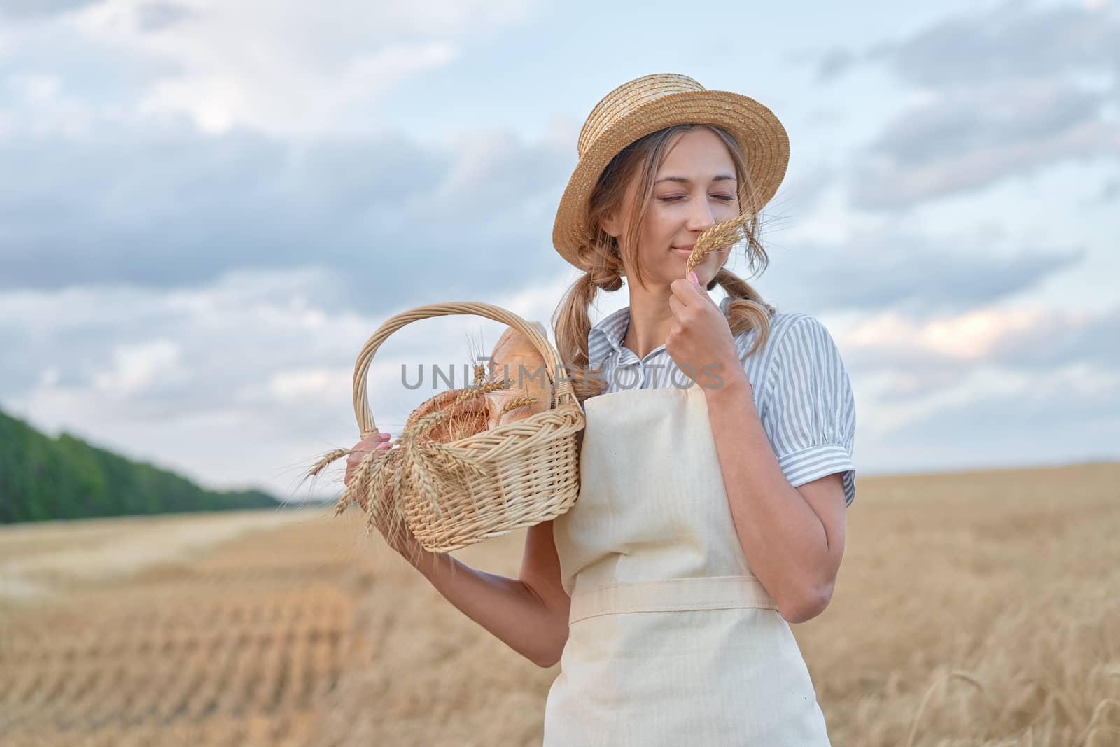 Female farmer standing wheat agricultural field Woman baker holding wicker basket bread product by andreonegin