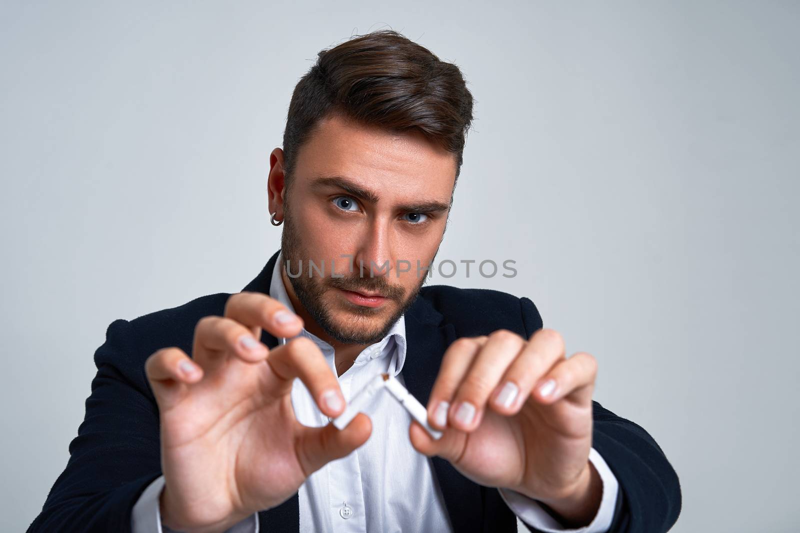 Businessman Business person. Man business suit studio gray background. Modern person breaks a cigarette stopped smoking Portrait of charming successful young entrepreneur