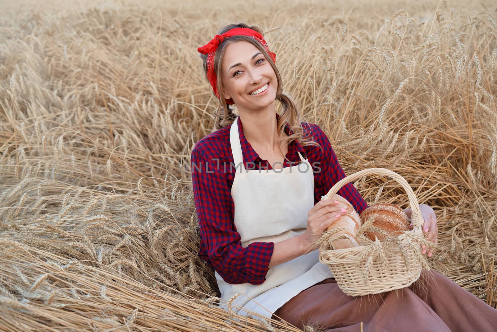 Female farmer sitting wheat agricultural field Woman baker holding wicker basket bread eco product Baking small business Caucasian person dressed red plaid shirt apron organic healthy food
