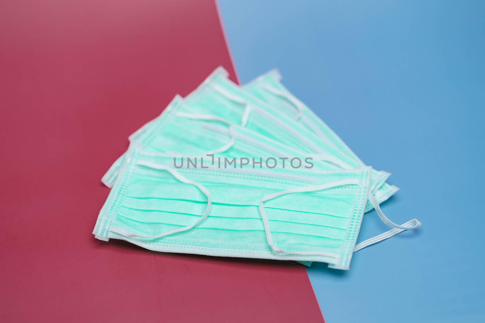 Face mask or protective raspiratory mask for spreading virus on two tone background (red and blue background).