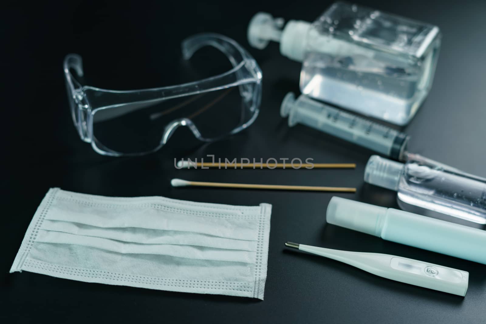 Corona virus medical equipment: Medical masks, safety glasses, syringe, cotton swab, sanitizer and thermometer with petri dish on the table. Coronavirus, Covid-19 protection.
