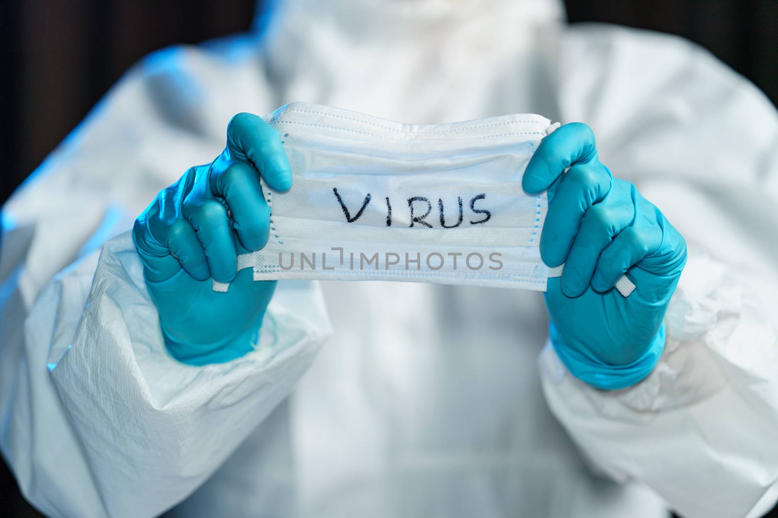 Scientist in hazmat suit, hand holding protective face mask with text virus.