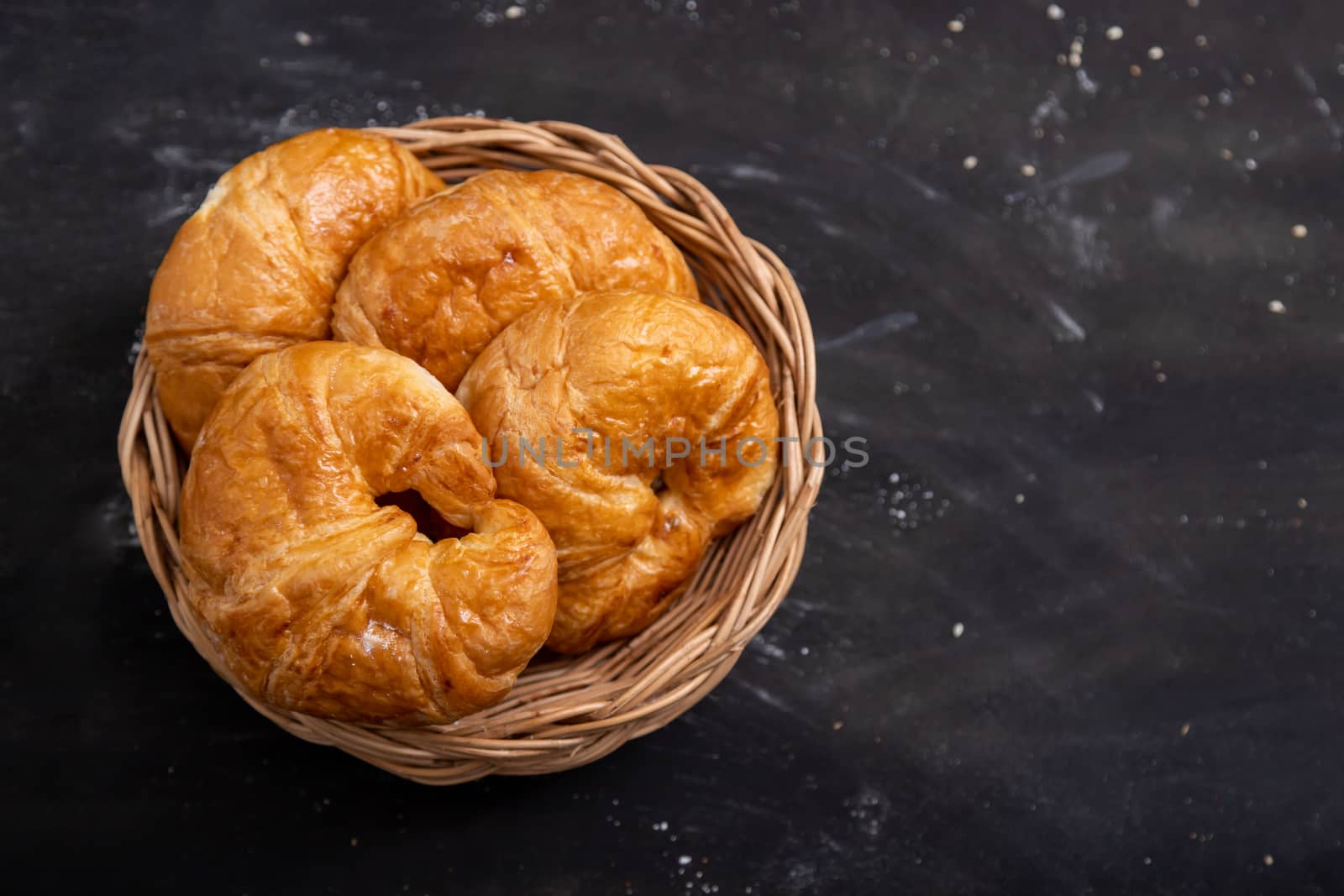 Top view Croissant in a wicker basket placed on a black floor that has messed up the pastry dough