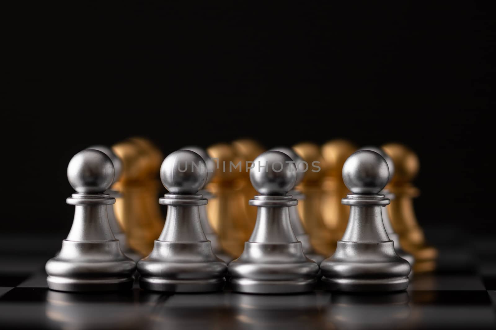 gold and silver chessman in the game on board with black background.