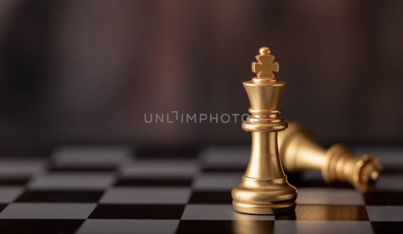 gold king standing and queen falling in game on chess board