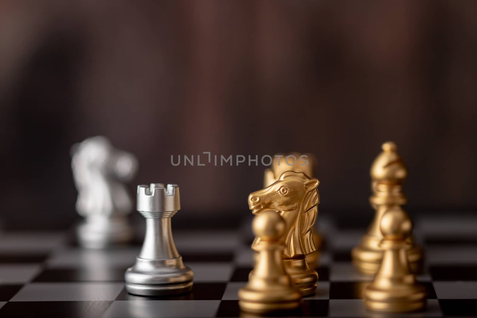 Silver and gold chess on the board and wooden background